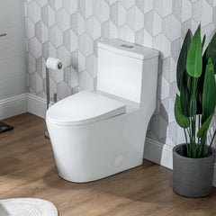 Modern white toilet in a bathroom with hexagonal tiles and a plant.